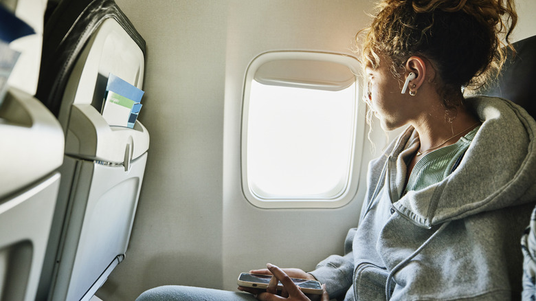 An illustrative image showing an individual looking out of the window of a commercial airplane.