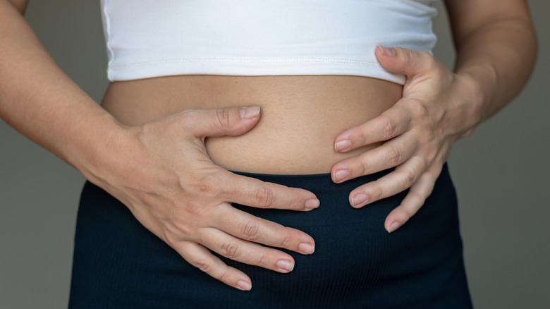 An illustrative image showing a woman holding her abdomen, appearing bloated and uncomfortable.