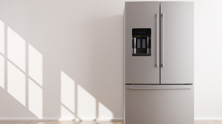A French door refrigerator against a white wall