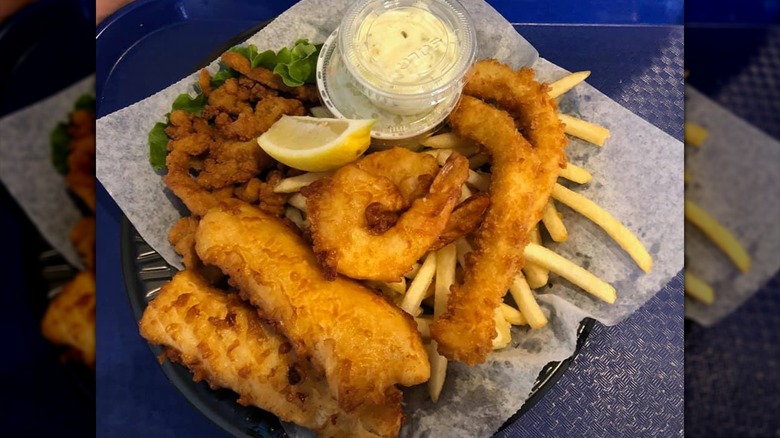 Plate of fried fish and shrimp atop pile of fries