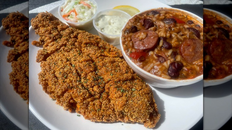 Fried catfish with red beans and rice, tartar sauce, and coleslaw cups on white plate