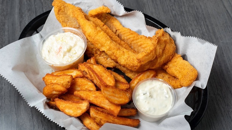 Fried Alaskan walleye with fries, tartar sauce, and coleslaw in black basket