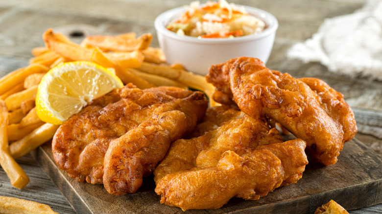 Fish and chips with lemon on wooden board