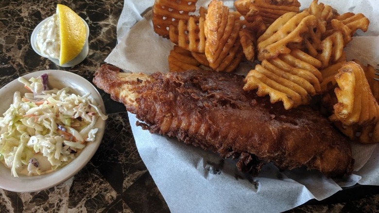 Fried fish with waffle fries, side of coleslaw, and lemon slice