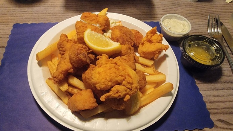 Plate of fried fish and fries with lemon and dipping cups on side