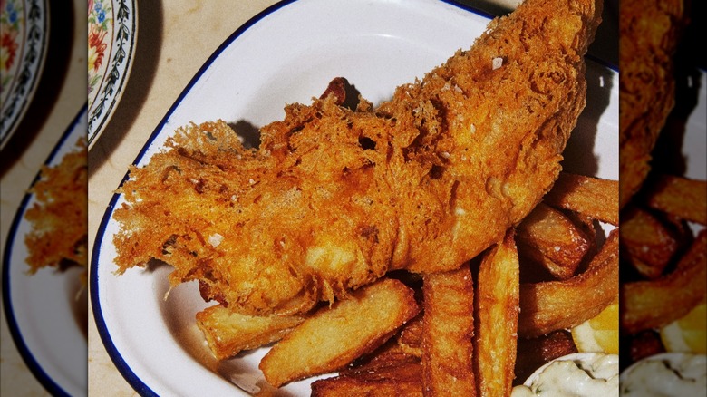 Battered fish with thick-cut fries on white plate