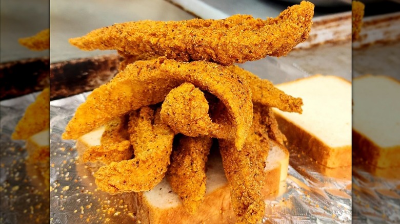 Pile of fried fish on slice of bread and aluminium foil
