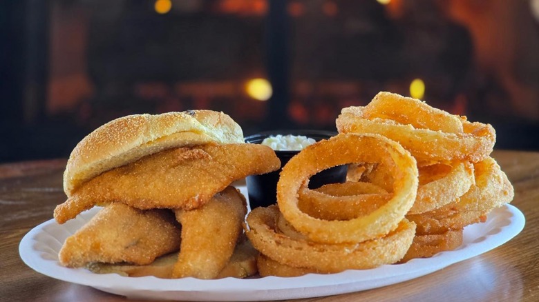 Fried fish filets on toasted roll with pile of onion rings