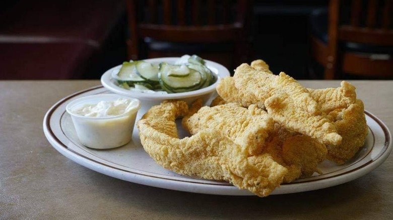 Fried catfish on plate with side of sliced cucumbers and tartar sauce