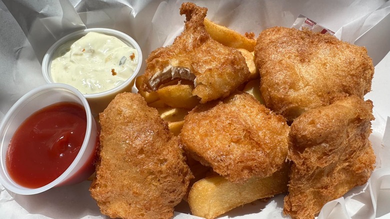 Pieces of fried albacore tuna on paper with tartar sauce and ketchup