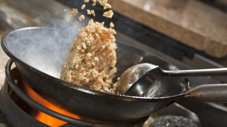 Fried rice being cooked in a frying pan on a hot stovetop