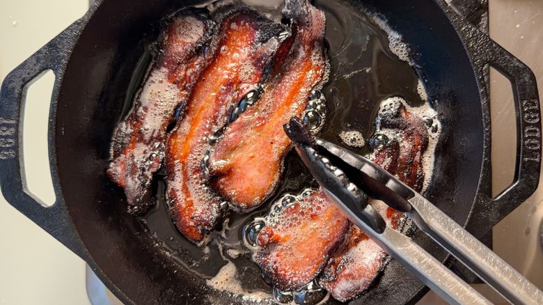 Bacon cooking in cast iron skillet on stovetop