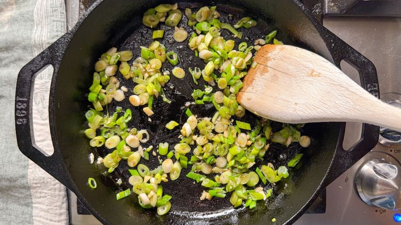 Sautéed scallions and garlic in cast iron pan on stovetop