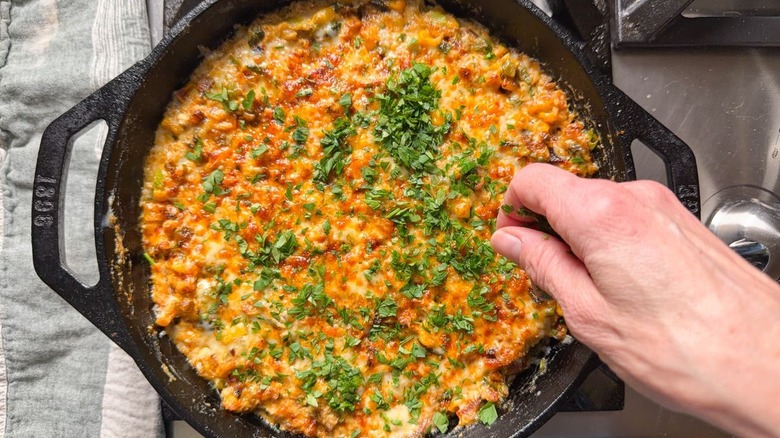 Garnishing best game day cheesy crab dip with chopped Italian parsley