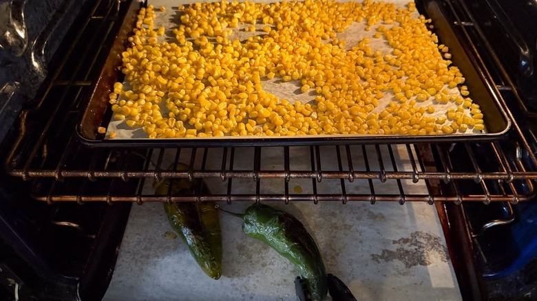 Corn and poblano peppers roasting on sheet pans in oven