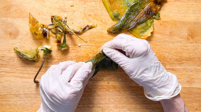 Peeling poblano peppers with gloved hands