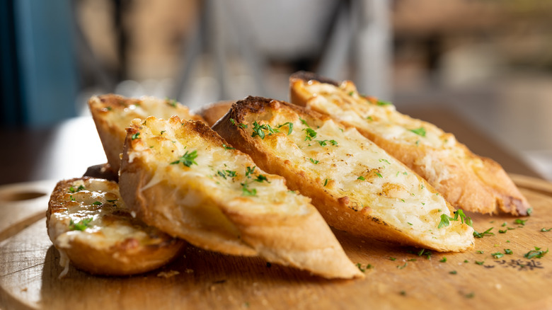Slices of garlic bread with herbs on cutting board