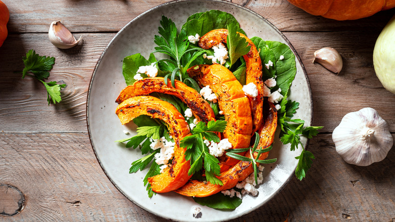 A bowl of greens topped with roasted pumpkin.