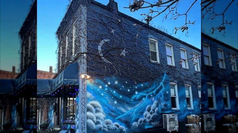 Side view of the exterior of Blue Moon Cafe, including a night sky mural on the building