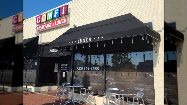 The exterior of Comfi with metal tables outside under a black awning