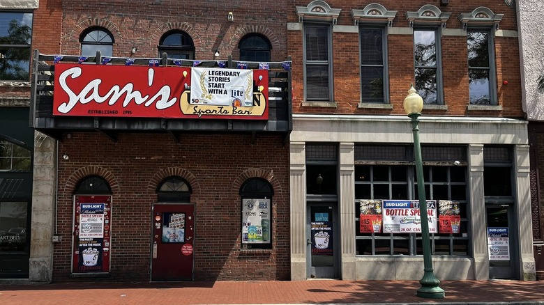 Front exterior of Sam's Uptown Cafe with a red restaurant sign hung on the balcony above