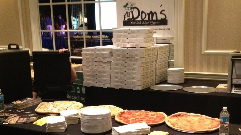 A display of pizzas in front of a stack of takeaway boxes at Dom's NY pizzeria