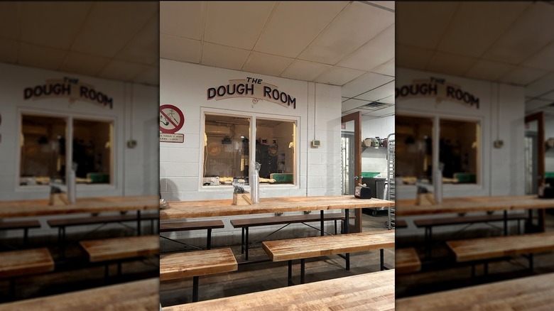 The interior of Antico Pizza with rustic benches and tables and a window into the kitchen