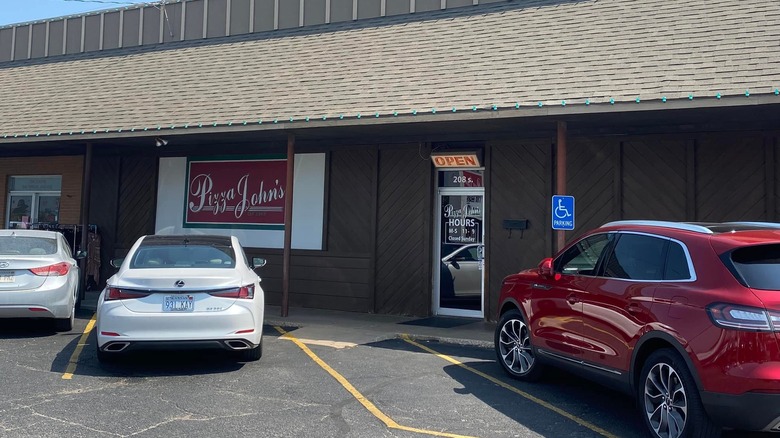 The exterior of Pizza John's with cars parked outside