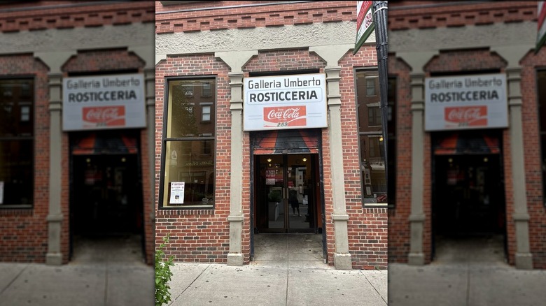 The red brick exterior of Galleria Umberto with a Coca-Cola sign above the door