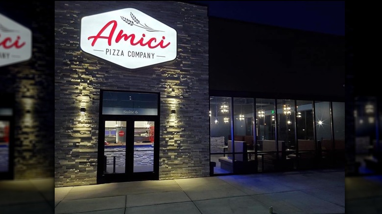 Exterior of Amici Pizza Company lit up at night