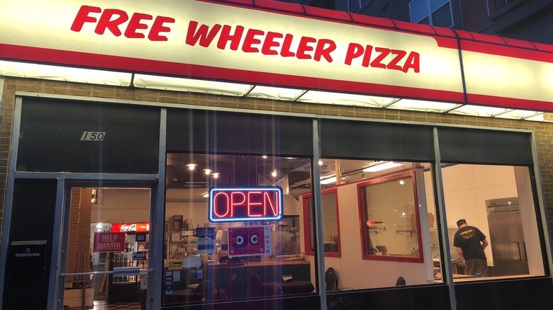 Exterior of Free Wheeler Pizza with the red sign lit up at night
