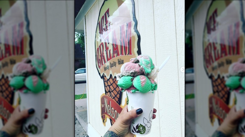 Hand holding a cup brimming with teal and pink ice cream outside Nelson's