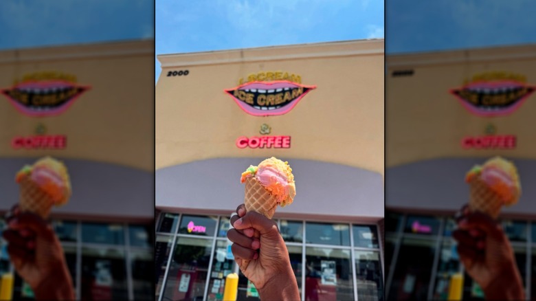 Hand holding a cone with colorful ice cream in front of I Scream Ice Cream