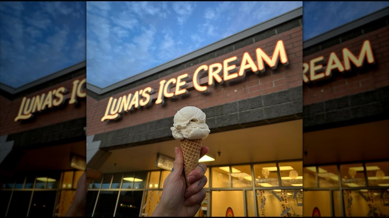Hand holding a cone of vanilla ice cream in front of Luna's Ice Cream