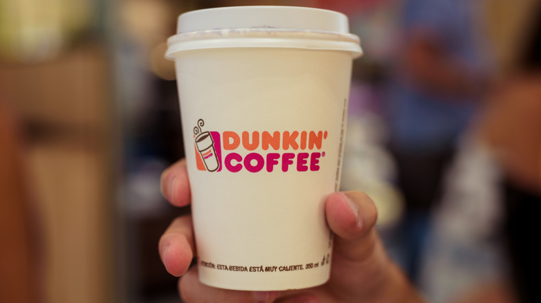 Person holding a Dunkin' coffee cup
