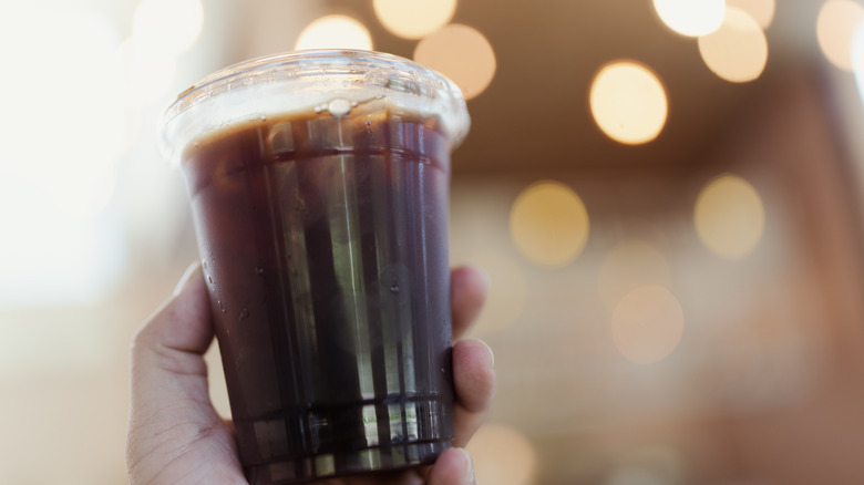 Cold brew coffee in plastic to-go cup with background of sparkling lights