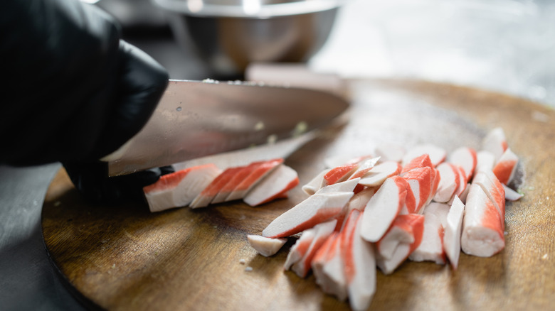 Chef slicing crab sticks on cutting board