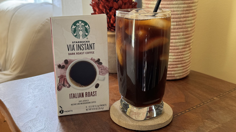 A glass of iced coffee on a table next to Starbucks Via Instant Coffee Packets