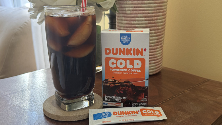 A glass of iced coffee on a table next to a package of Dunkin' Cold Powedered Coffee
