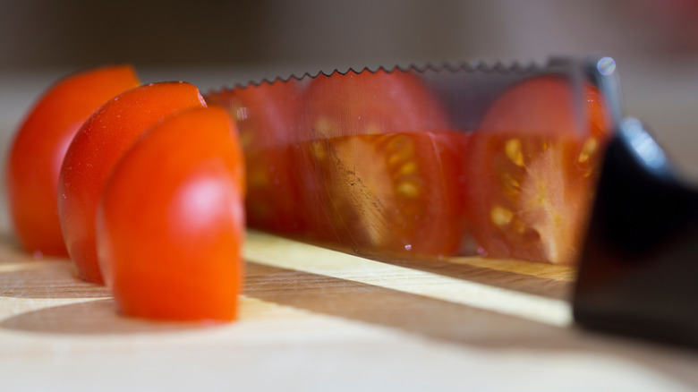 Chopped tomatoes next to a serrated knife