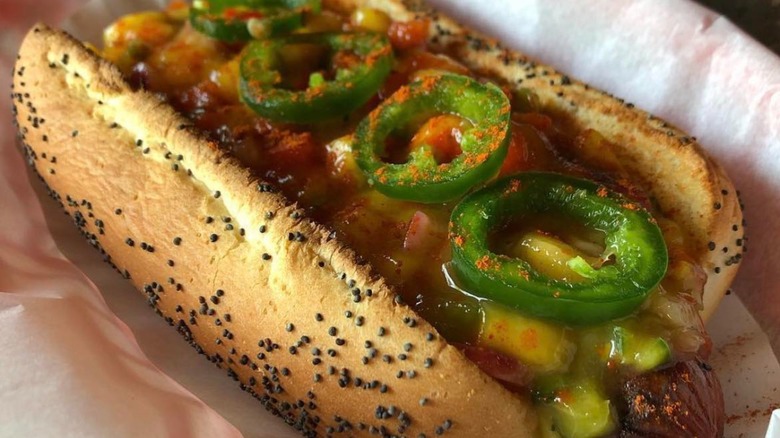 Hot dog with jalapeños, mango, and salsa on a poppyseed roll