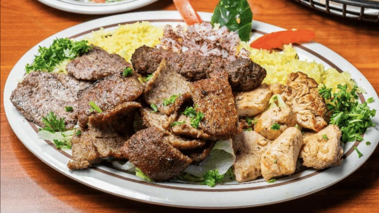 Gyro meat, chicken, and rice with vegetables on white plate