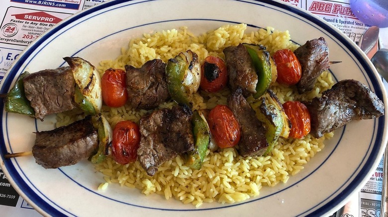 Beef kabobs on a bed of rice on diner plate