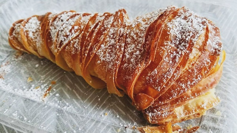 Lobster tail pastry with powdered sugar in plastic container