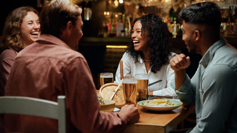 Four people sitting at a table with food and drinks at night
