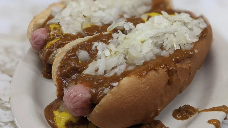 Two chili dogs with onions and mustard on plate