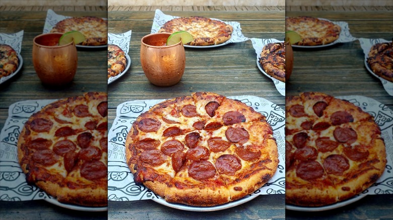 Pepperoni pizza on paper with Moscow mule mug in background