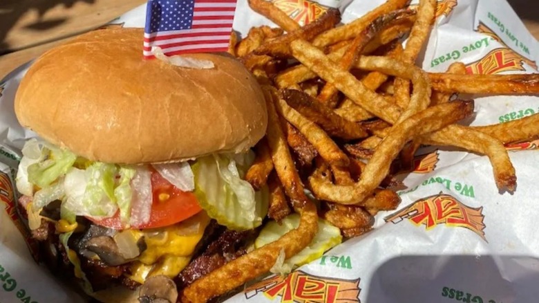 American flag skewer stuck into burger with lettuce and tomato with side of fries