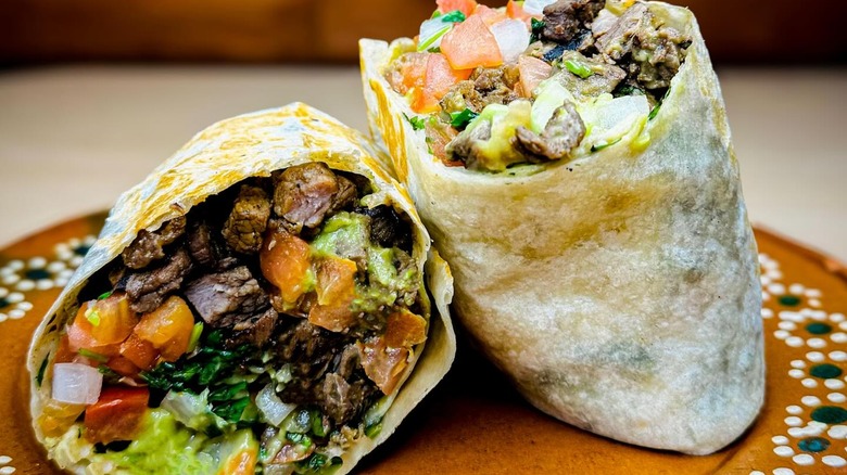 Steak burrito cut in half on colorful plate