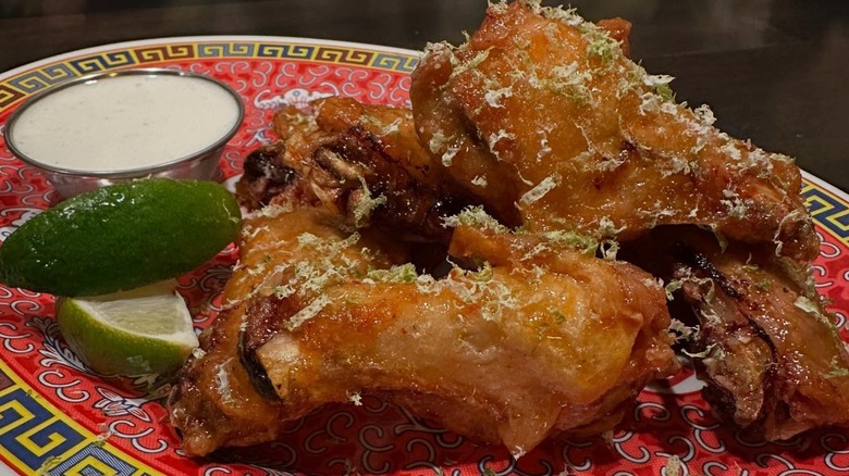 Chicken wings with slices of lime and dipping sauce on colorful plate